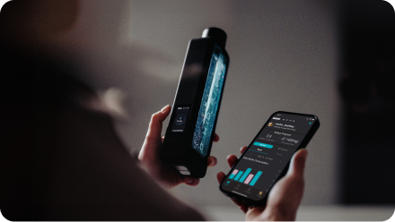 Person holding a hydrogen water bottle and smartphone app displaying water stats