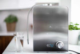 Stainless steel hydrogen water machine with glass of water on kitchen counter